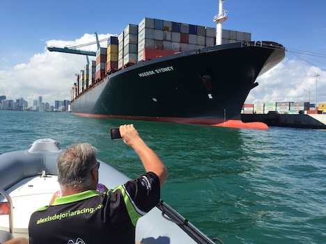 Passengers on a boat tour in Miami photographing a huge cargo ship at Port Miami.