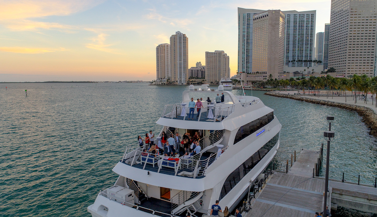 A birthday party group celebrates at sunset on a yacht charter in Miami.