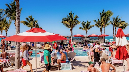 A lot of people enjoying a day by the pool in bimini with frozen drinks and bright blue skies.