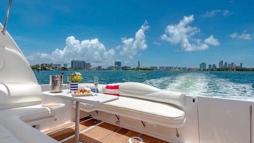 A glass of champagne sits at the stern of a private yacht during a sunset cruise in miami overlooking the skyline
