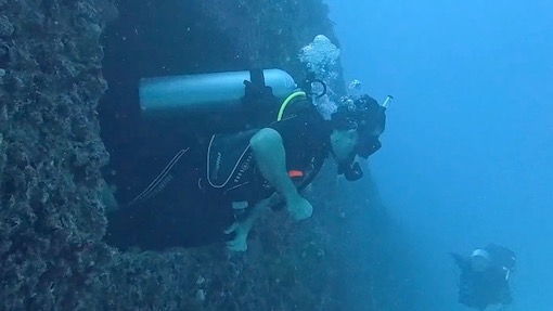 An underwater shot of a scuba diver exiting the hull of a sunken ship off the coast of Miami during a wreck dive. 