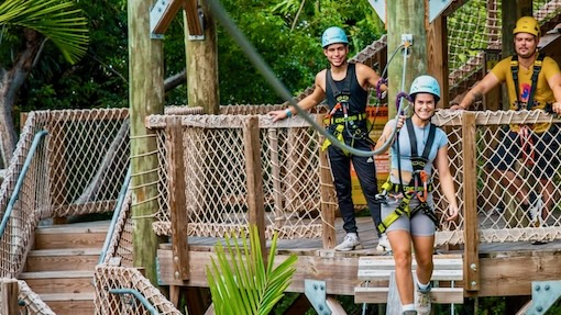 A family having fun in Miami at Jungle island overlooking biscayne bay on a tree top zip line experience.